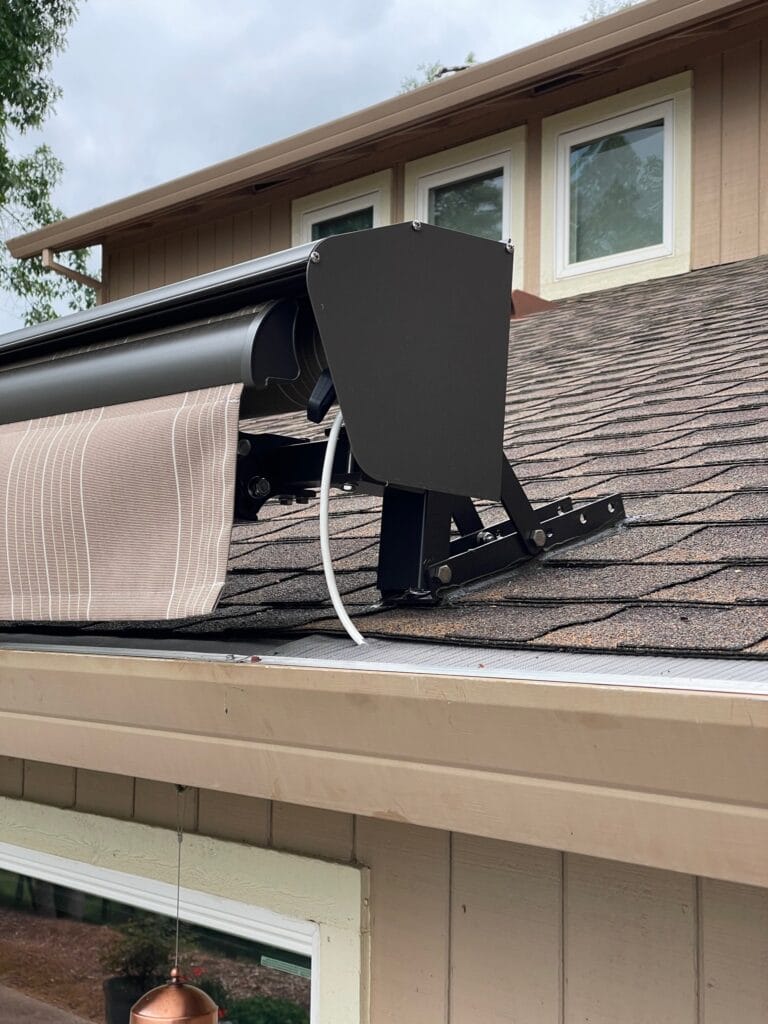 Retractable awning mounted on a shingled house roof